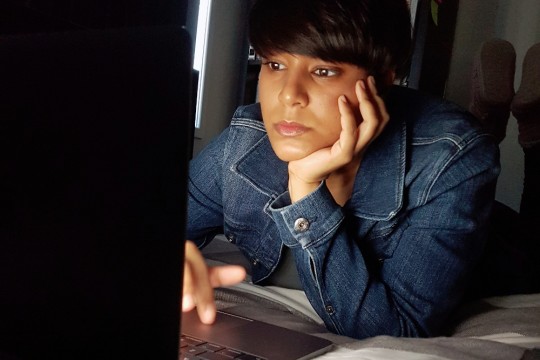 A young woman looking at a laptop screen.